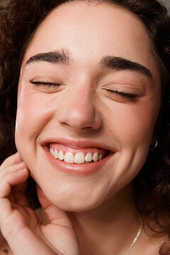 Smiling Woman With Curly Hair Showing Teeth in Indoor Setting