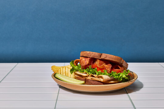 A Hearty Turkey and Bacon Sandwich Served With a Crisp Pickle And Chip