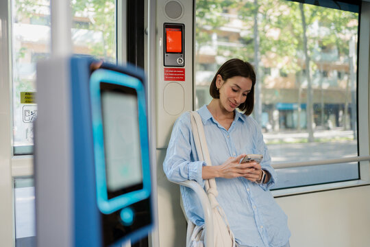 Woman Checking Mobile Phone Inside Tram on Sunny Day