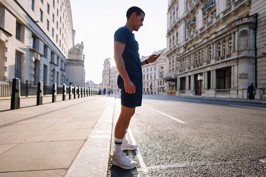 Young man using smartphone during running break in London