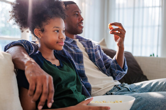 Father and daughter bonding while eating popcorn at home