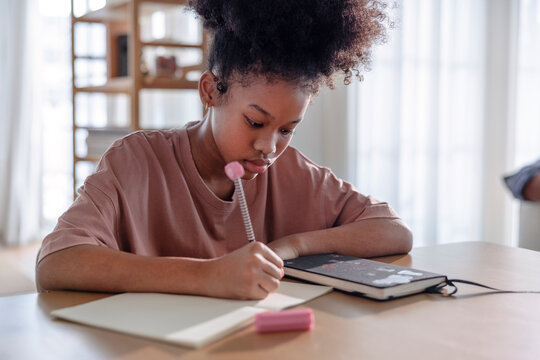 Focused young girl writing in her notebook at home