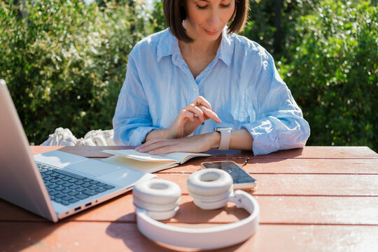 Woman checking her smartwatch while working at Park Table