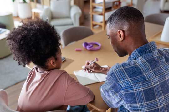 Father helping his daughter with her studies at home