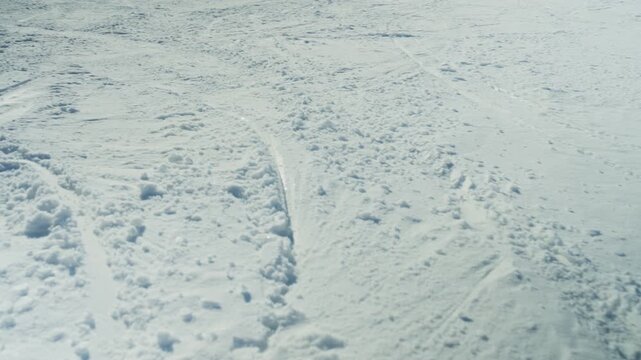 Fresh ski tracks mark a pristine snow-covered mountain slope on a clear winter day. The vast expanse of white snow captures the essence of winter sports and natural beauty.