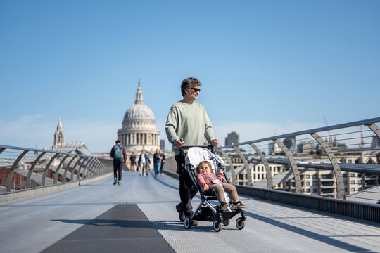 Father Pushing Baby Stroller Across Millennium Bridge In London
