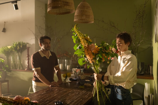 Florist woman shows bouquet to man client in flower shop