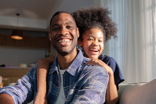 A joyful Black father and daughter sharing a hug