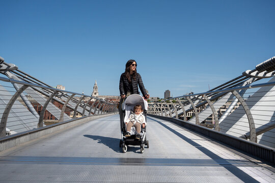Mother Pushing Baby Stroller Across Millennium Bridge In London