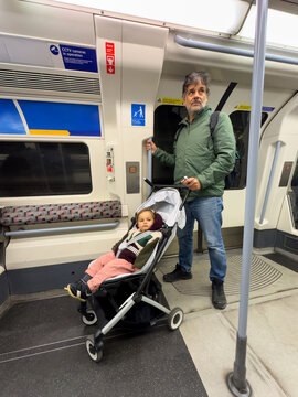 Father Traveling With Baby Stroller On London Underground Train
