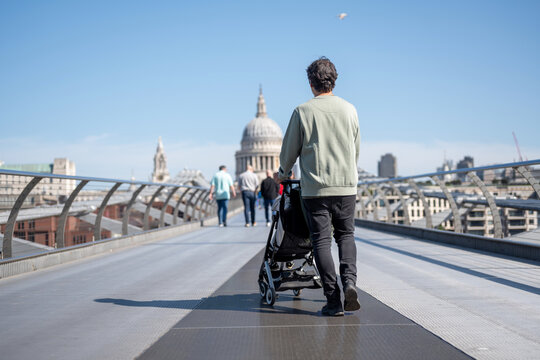 Father Walking With Baby Stroller Across London Millennium Bridge