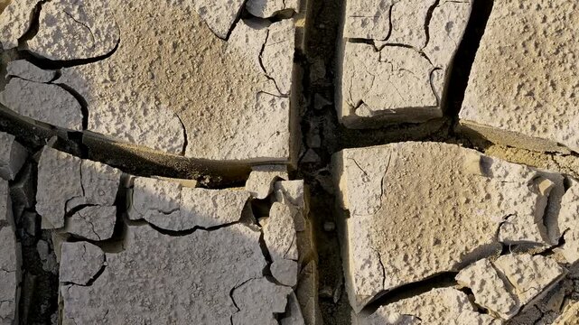 Tire track running through dry, cracked mud ground representing drought, climate change, and water scarcity concept