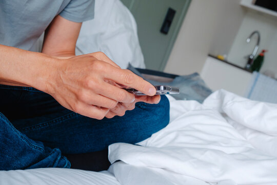 a man uses his smartphone while sitting on an unmade bed