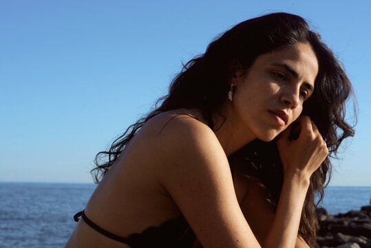 Woman sits by the sea during golden hour