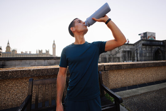 Young man drinking water during workout in London