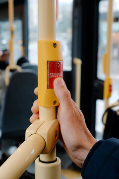 a close-up of a man pressing the stop-request button on a Swedish bus