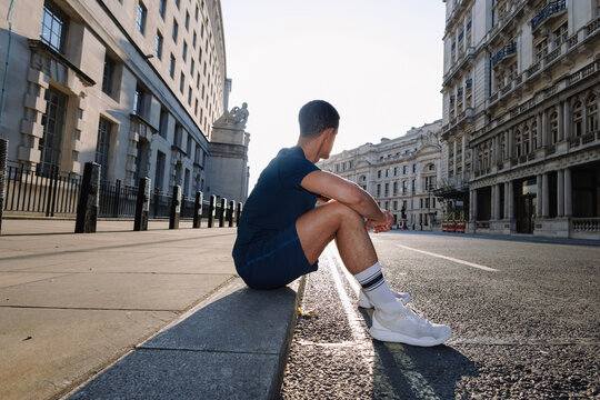 Young man resting during urban running training in London