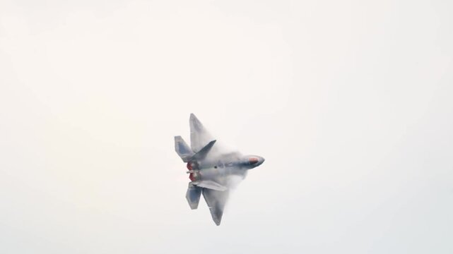 An F-22 Raptor Stealth Fighter Ascends Rapidly as Vapor Condensation Envelops Its Fuselage Against an Overcast Sky.