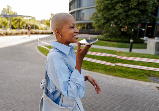 Young woman speaking into smartphone using voice assistant