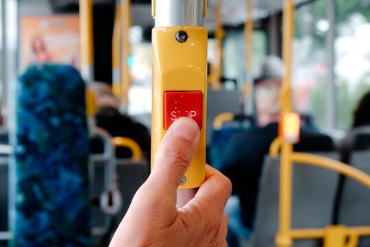 a man presses the red stop button on a city bus