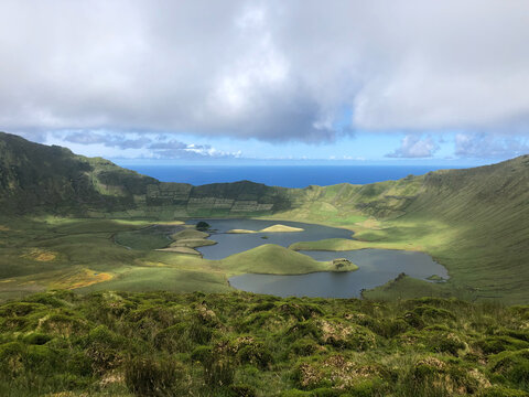 Sunlight sweeping across the lakes and cinder cones on the floor of the Caldeirao crater, Corvo Island, Azores, Portugal