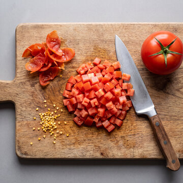 Tomato concass&eacute; peeled seeded and diced into uniform cubes on wooden cutting board