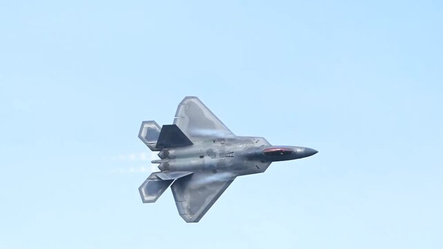 An F-22 Raptor Stealth Fighter Soars Horizontally Across a Clear Light-Blue Sky.