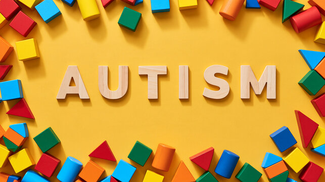 Wooden letters spelling the word autism surrounded by colorful geometric toys on a yellow background. Developmental disorder concept for pediatric education ads.
