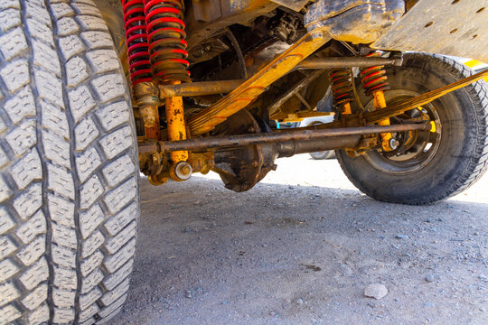 Detailed low-angle view Old School Leaf Spring and double coils off-road Vehicle Suspension and Knobby Tire. 1988 heavy-duty tech.
