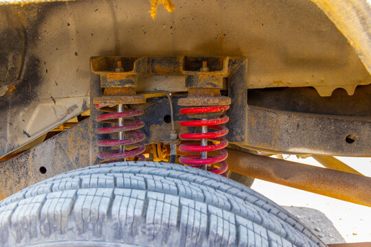 Close-Up of Rusty Off-Road Vehicle Suspension with dual spring and dual shock absorbers mounted on rusty bracket.