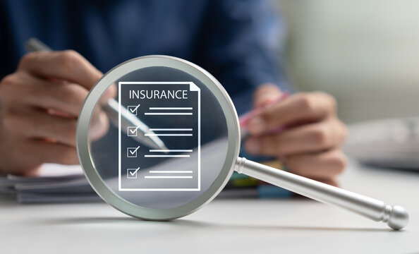 Insurance policy review concept with magnifying glass highlighting coverage checklist while a professional completes paperwork, representing risk assessment, protection, claims, financial planning.