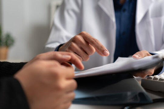 Doctor discusses medical documents with a patient during a healthcare consultation, reviewing information and explaining treatment, diagnosis, clinical care, and professional medical advice.