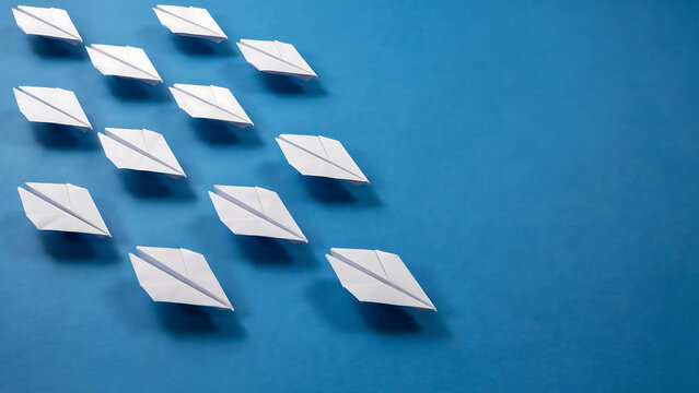 Group of white paper airplanes flying in a formation on a blue background with paper airplane paper plane business strategy paper craft formation leadership innovation teamwork creative