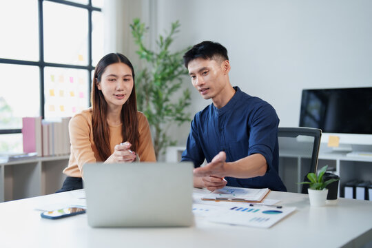 Asian business colleagues discussing project strategy and planning during an informal meeting, collaborating on startup growth and creative solutions in a modern office