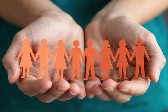 Hands holding a paper chain of diverse people representing unity and community