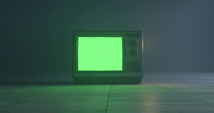Vintage television turning on with green screen display and rotating knobs in dark foggy room