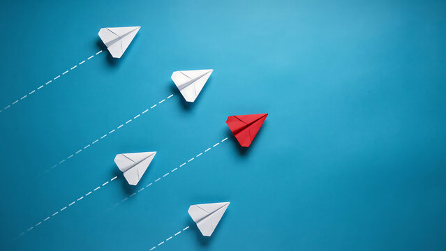 Single red paper airplane leading a group of white paper airplanes on blue background with red plane group dynamics standing out business strategy leadership concept innovation differentiation
