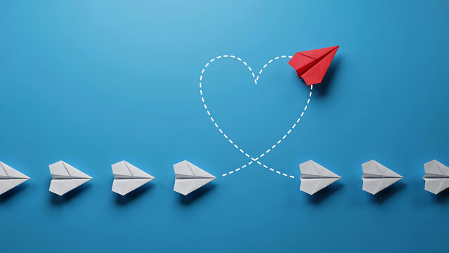 A red paper plane flying in a heart shape path away from a row of white paper planes with flight path blue background love concept individuality difference creative decision direction dreaming