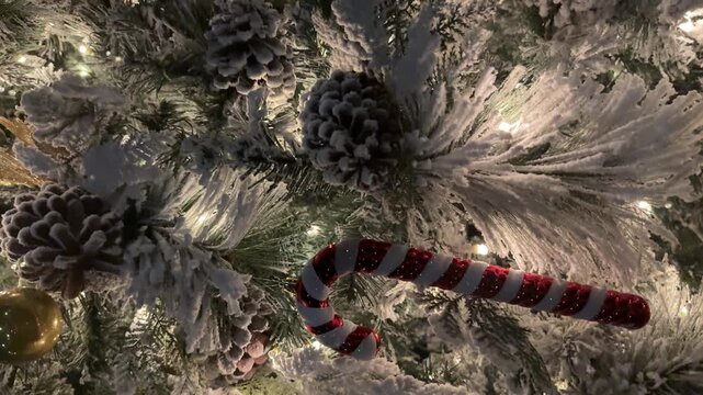 vertical White Christmas tree with candy cane and pine cone ornaments, festive close up