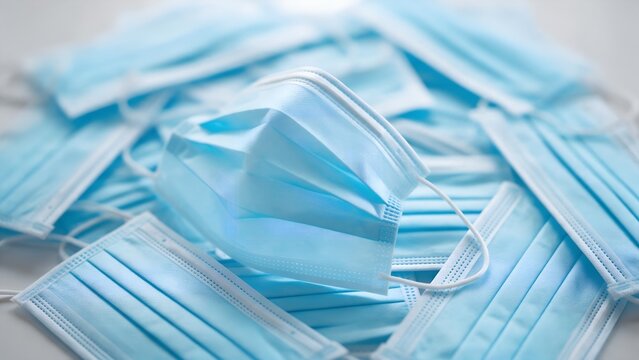 Surgical blue face masks stacked in a pile representing medical protection equipment for viral prevention and health safety protocols in a clinical or hospital healthcare environment