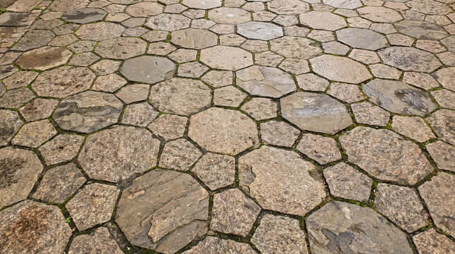 Ancient stone pavement with polygonal paving slabs forming an irregular geometric pattern background. Concept of tessellation, cobblestone texture, stone walkway, outdoor flooring, flagstone.