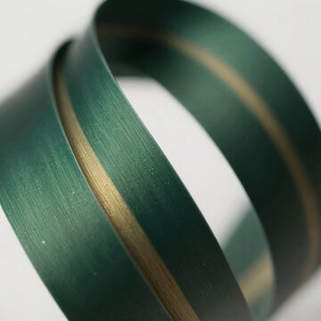close roll green tape tape appears metal similar material has shiny metallic finish edges tape thin curved darker green color one side lighter green background white making green tape stand out taken