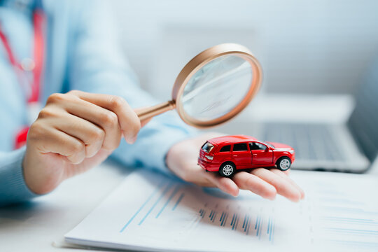 Person hand magnifying glass miniature red vehicle car inspect focused