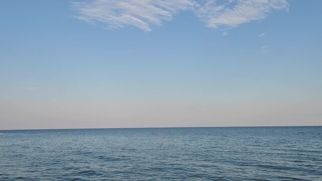 Cirrocumulus clouds form delicate ripples across the sky as high-altitude ice crystals are shaped by winds. A rocky Mediterranean headland, beach umbrellas and a calm sea complete this peaceful summer