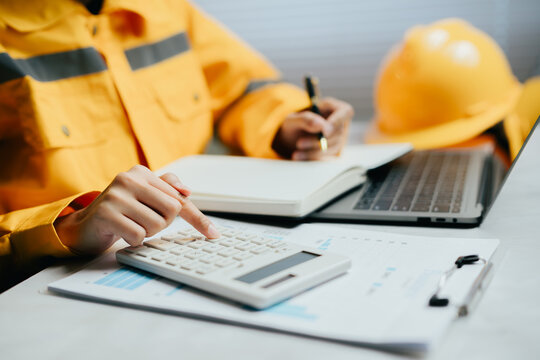 Professional construction engineer calculating project budget with focused expression while working on financial document at office