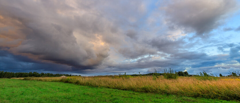 Storm clouds roll across horizon over open meadow at dusk
