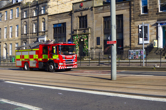 Red Scottish Fire and Rescue Service fire engine driving along a sunny city street in Edinburgh.