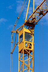 Yellow construction tower crane cabin against clear blue sky © Alexander