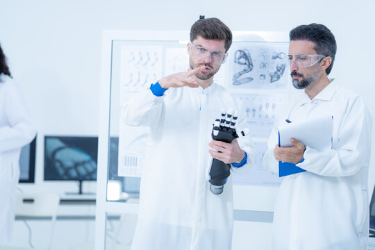 Robot motion tuning by demonstration, a researcher mimes the wrist angle he is after while his colleague holds the tablet that will capture the new joint setting