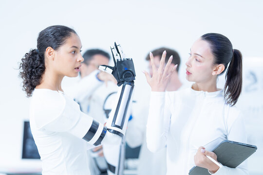 Robotic hand teleoperation mirrored: the wearer opens the bionic fingers wide while her colleague matches the shape with her own hand to check the flexion envelope